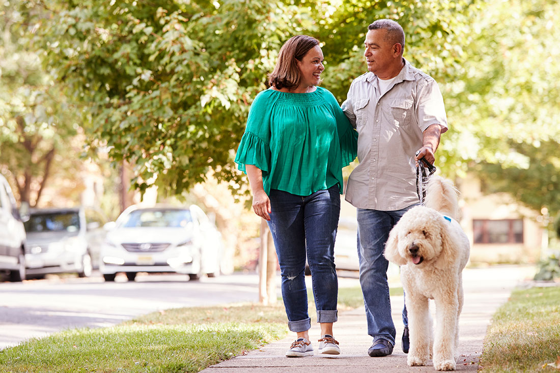 Middle aged couple walking their dog down the street