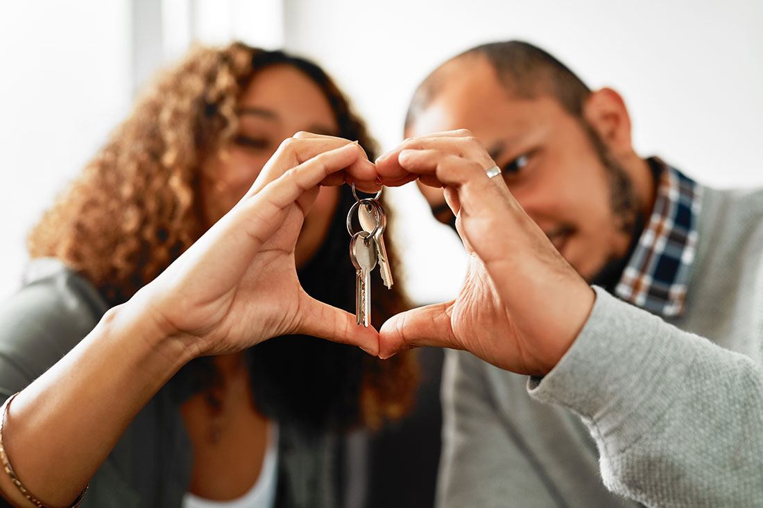 Couple holding keys to their apartment with heart-shape hands